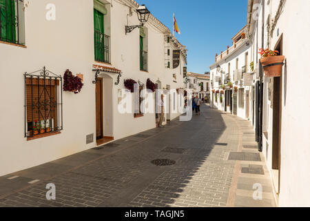 E la stretta strada di ritorcitura con pareti bianche case nel pittoresco villaggio di montagna di Mijas, regione Andalusia, Spagna Foto Stock