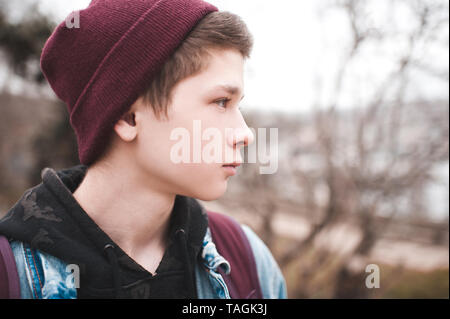 Ritratto di teen boy 17-18 anno indossando berretto lavorato a maglia all'aperto vicino. Foto Stock