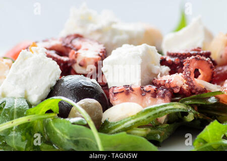 Insalata di polipo con rucola, olive e formaggio feta sulla piastra bianca Foto Stock