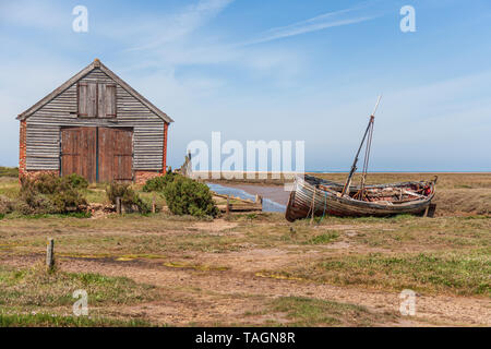 Vista del vecchio capannone di carbone e la vecchia barca di legno a thornham porto sulla Costa North Norfolk Foto Stock