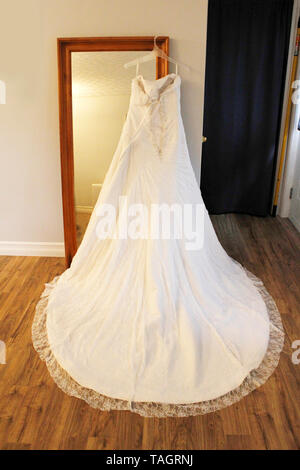 Splendida vista posteriore di un pizzo bello abito da sposa con un round bel treno appeso su uno specchio Foto Stock