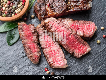 Mezzo raro Ribeye con erbe aromatiche sulla scheda di grafite. Foto Stock