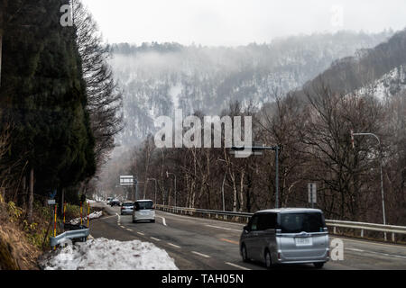Takayama, Giappone - Aprile 8, 2019: Foresta in primavera nella Prefettura di Gifu con la strada che conduce a Okuhida villaggi e Shinhotaka funivia con vetture in w Foto Stock