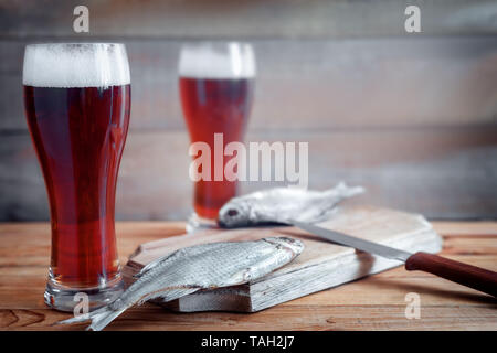 Sul tavolo della cucina pensione con pesci secchi, roach, accanto a due bicchieri di birra. Foto Stock