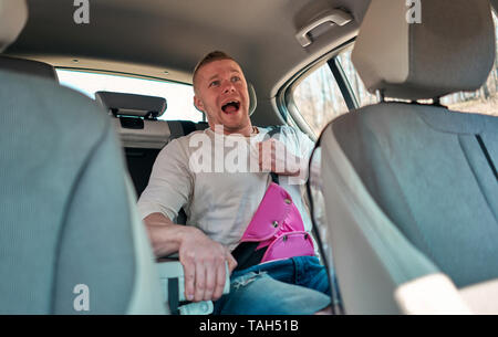 Adulto Uomo indossare bambino cintura di sicurezza in auto nel sedile posteriore Foto Stock