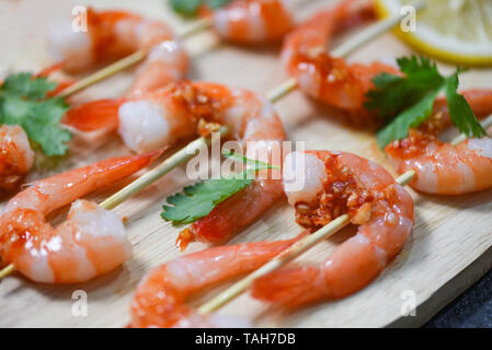 Piatto di frutti di mare con gamberi spiedini cucinati di frutti di mare con salsa di erbe e spezie su uno sfondo di legno / Close up crostacei di gamberi cotti Foto Stock