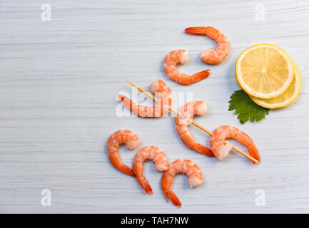 Frutti di mare con gamberi ocean cena gourmet cucinato con prezzemolo e limone spiedini di gamberi decorare bianco su uno sfondo di legno Foto Stock