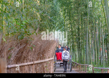 Tirate il rickshaw riding turisti attraverso una foresta di bamboo percorso ad Arashiyama, Kyoto, Giappone Foto Stock