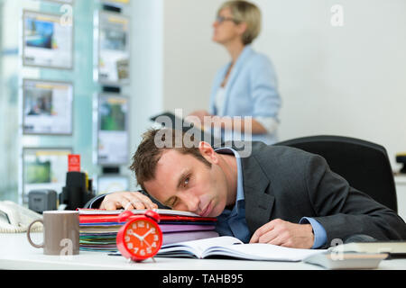 Imprenditore addormentato crollati sulla cartella in ufficio Foto Stock