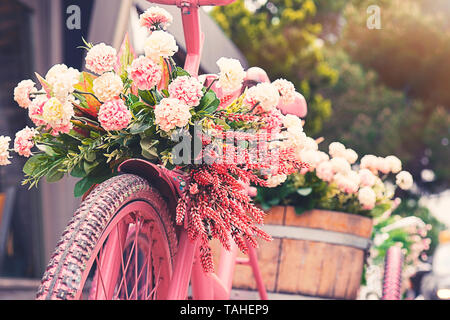 Rusty triciclo bike con vaso di fiori nel vassoio contro sfondo blured Foto Stock