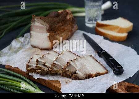 In casa la pancetta affumicata e le cipolle verdi sono collocati su uno sfondo scuro, orientamento orizzontale Foto Stock