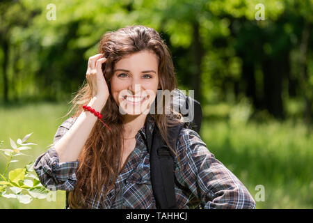 Ritratto di ragazza sorridente turista con zaino su sfondo di foresta Foto Stock