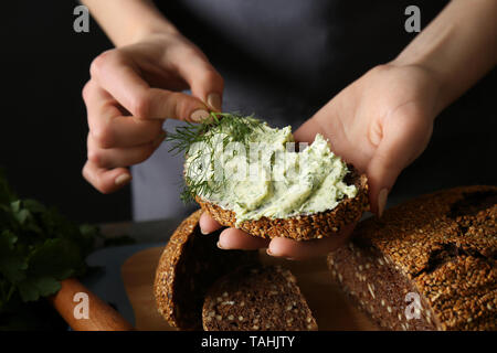 Giovane donna holding pezzo di pane fresco con burro verde, primo piano Foto Stock