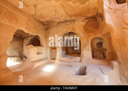 Antichi affreschi sulle rovine delle mura di pietra di un antica chiesa scavata di una vecchia roccia arenaria nella valle della Cappadocia, vista da vicino Foto Stock