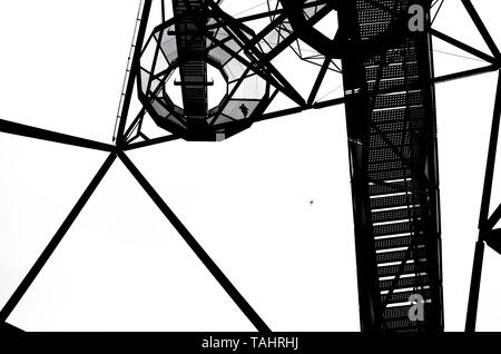 Foto in bianco e nero della costruzione di un tetraedro in tedesco Bottrop con la scalinata che conduce alla sommità del punto di riferimento. La foto è stata presa da sotto contro il cielo. Foto Stock