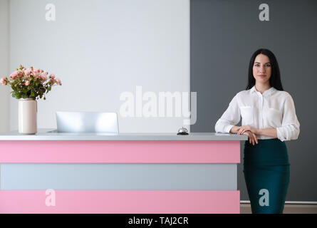 Receptionist femmina vicino alla scrivania in hotel Foto Stock