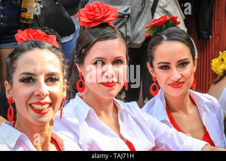 South Bank di Londra, Regno Unito - 25 maggio 2019. Tre splendidamente vestita flamenco dancers prendere un periodo di riposo sul prato. La Feria de Londres è un free festival a Londra il South Bank presentando la cultura spagnola, danza, musica, cibo e vino da maggio 24-26. Credito: Imageplotter/Alamy Live News Foto Stock