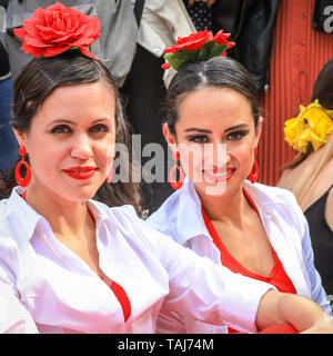 South Bank di Londra, Regno Unito - 25 maggio 2019. Tre splendidamente vestita flamenco dancers prendere un periodo di riposo sul prato. La Feria de Londres è un free festival a Londra il South Bank presentando la cultura spagnola, danza, musica, cibo e vino da maggio 24-26. Credito: Imageplotter/Alamy Live News Foto Stock