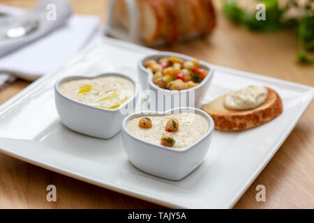 Houmous e ceci insalata snack serviti con pane tostato sul lato. Foto Stock