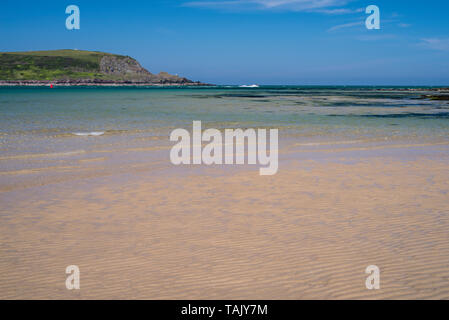 Una tranquilla giornata di sole a Daymer Bay, Trevetherick in North Cornwall, Regno Unito con bassa onde che lambiscono la spiaggia di sabbia Foto Stock