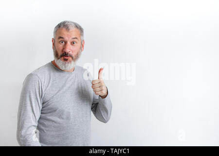A mezza lunghezza Ritratto di un grave grey-haired uomo barbuto in grigio di una t-shirt su uno sfondo bianco. Foto Stock