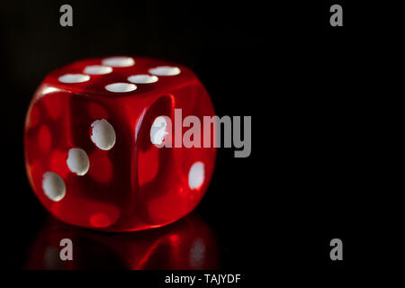 Primo piano di una dadi rossi con un numero vincente sulla faccia superiore su un nero superficie a specchio, concetto vincente Foto Stock
