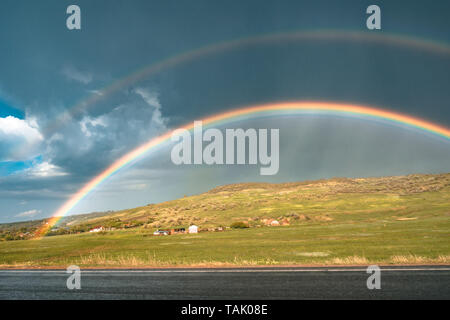 Rainbow su strada con le nuvole in cielo, dark sky piovoso al di fuori. Rainbow tempesta e allo stesso tempo Foto Stock