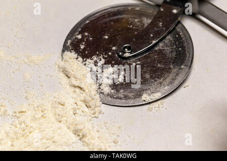 Un tagliapizza in appoggio in farina. Foto Stock