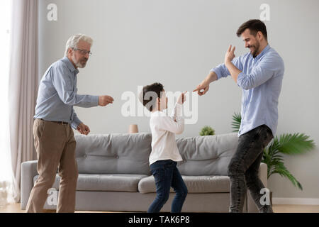 Entusiasta il padre e il figlio e nonno divertirsi impegnati in divertenti attività per il tempo libero rilassandosi insieme a casa felici tre generazioni di uomini resto entertai Foto Stock