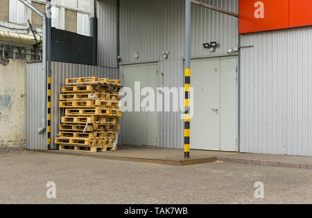 Vista su pallet, contenitori usati, scatole di fronte alla porta del magazzino o dello store Foto Stock