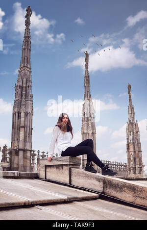 Giovane donna seduta sul tetto del Duomo di Milano Foto Stock