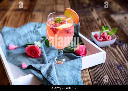 Il lampone rinfrescante peach mimosa bere su un sfondo di legno Foto Stock