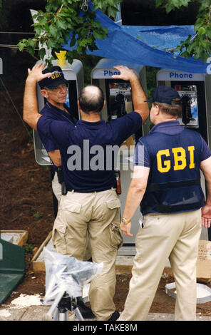 Gli investigatori del FBI e GBI (Georgia Bureau of Investigation) polvere di telefoni a pagamento per le impronte digitali da sinistra il Parco Olimpico bomber dopo che egli ha chiamato in una minaccia di attentato dinamitardo alla polizia spedizionieri. Qualche istante dopo la bomba esplosa. Gli agenti sono anche adoperando la bomba raggio per raccogliere prove. Foto Stock