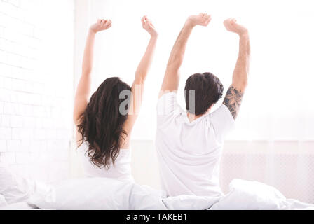 Ben riposati coppia giovane stretching su letto di mattina Foto Stock