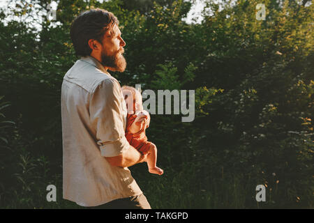 Padre holding neonato Bambino camminare insieme nella foresta outdoor famiglia felice lifestyle papà viaggiare con bambino padri giorni di vacanza Foto Stock