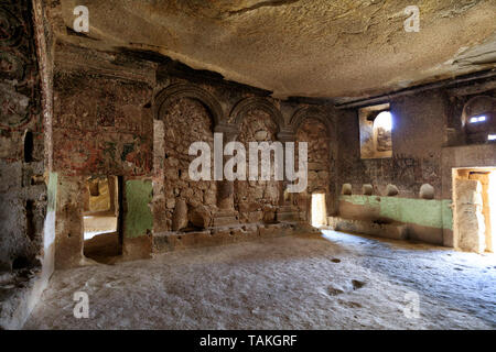 Antichi affreschi sulle rovine delle mura di pietra di un antica chiesa scavata di una vecchia roccia arenaria nella valle della Cappadocia Foto Stock