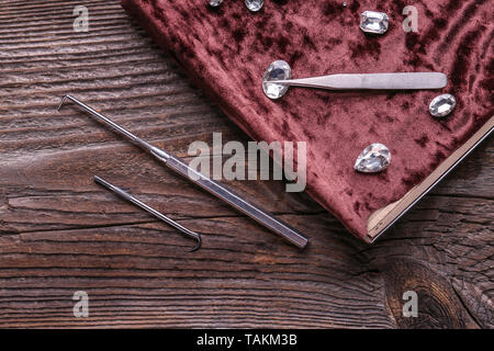 Scatola con pietre preziose e da gioielliere strumenti sul tavolo di legno Foto Stock