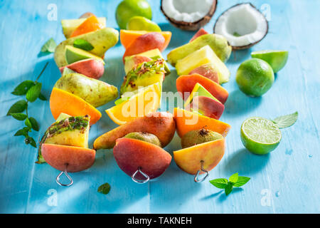 Spiedini dolci con mix di frutta sul tavolo blu Foto Stock