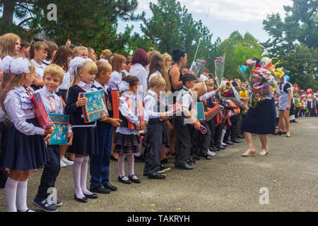 Adygea, Russia - 1 Settembre 2018: scolari e primo-livellatrici con doni nelle loro mani alla parata di gala il giorno della conoscenza Foto Stock