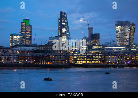 11 gennaio 2017, Londra, Regno Unito. Luna piena dietro le nuvole sopra grattacieli nella città di Londra con office luci riflesse nel fiume Tamigi. Foto Stock