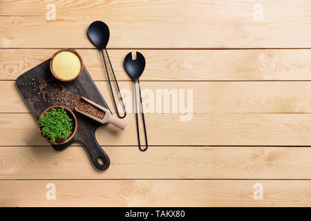 Set di utensili da cucina con grani sul tavolo di legno Foto Stock