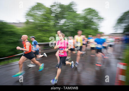 I concorrenti che partecipano nel 2019 Edinburgh Festival maratona mezza maratona Correre attraverso i giardini di Princes Street sotto la pioggia. Foto Stock