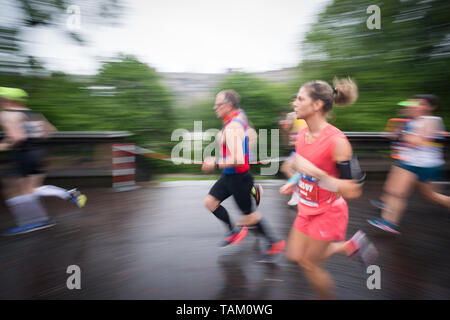 I concorrenti che partecipano nel 2019 Edinburgh Festival maratona mezza maratona Correre attraverso i giardini di Princes Street sotto la pioggia. Foto Stock