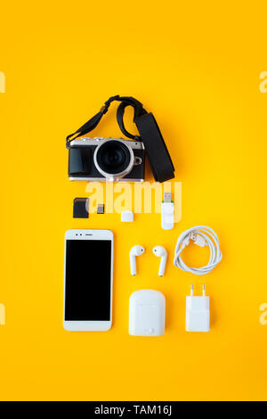 Impostare per blogger, creatore di contenuti o viaggiatore. Fotocamera Mirrorless, smartphone e gli accessori, sfondo giallo Foto Stock