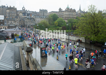 I concorrenti che partecipano nel 2019 Edinburgh Festival maratona mezza maratona Correre attraverso i giardini di Princes Street sotto la pioggia. Foto Stock