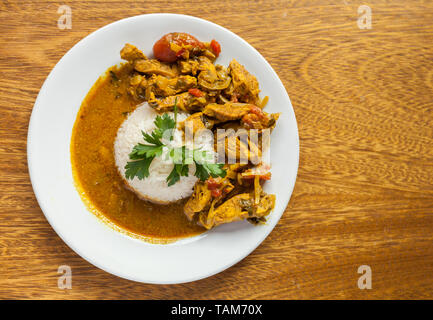 Pollo e curry luminose succosa con riso in bianco sulla piastra su sfondo di legno. Vista superiore, piatto laici. Stock Photo Foto Stock