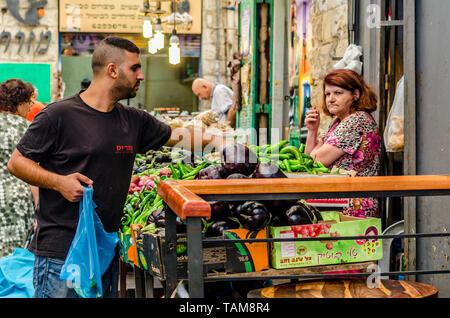 Gerusalemme, Israele- Agosto 16, 2016: Donna di fumare durante la vendita di un giovane uomo di verdure in Mahane Yehudah mercato di Gerusalemme, Israele Foto Stock