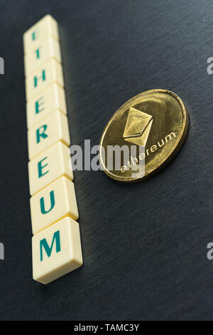 Ethereum fisico moneta in oro con testo realizzati al di fuori della lettera di piastrelle. Cryptocurrency. Orientamento verticale. Foto Stock