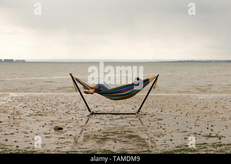 Southend on Sea, Regno Unito. 26 Maggio, 2019. Un uomo riposa in una amaca come la marea si spegne a Westcliff on Sea. Scene di Leigh e Southend on Sea, Essex, come la gente ottiene fuori per godere del lungo weekend. Penelope Barritt/Alamy Live News Foto Stock