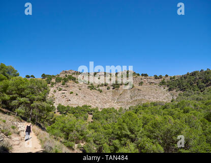 Una donna sul sentiero di El Santo picco, sopra la città di Alora in un caldo pomeriggio di aprile. In Andalusia, Spagna. Foto Stock